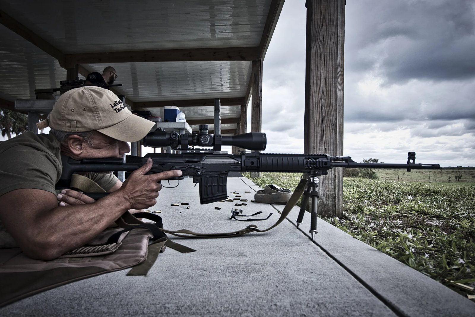Precision rifle shooter behind a scoped rifle at an outdoor range